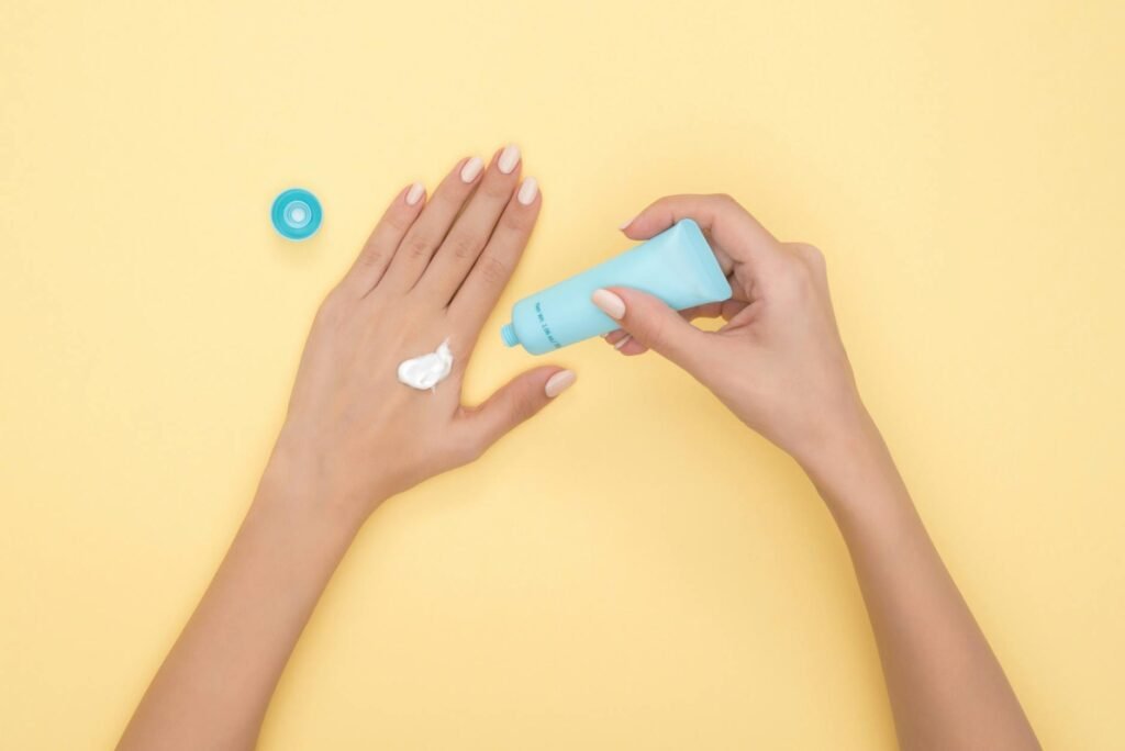 A gentle cleanser, cream moisturizer, and sunscreen arranged on a bathroom shelf.