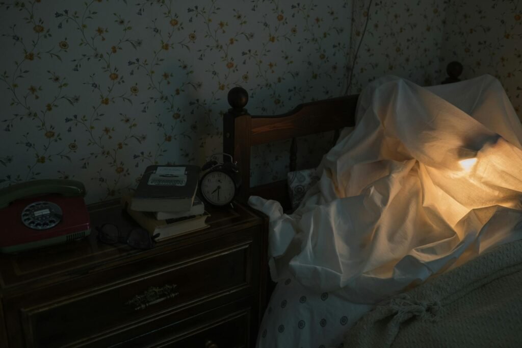 A calm bedroom corner with a book, lamp, and empty teacup