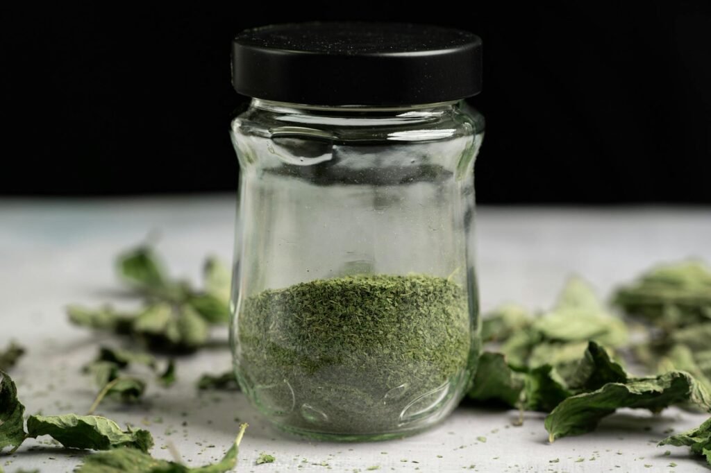 Fresh herb bunches beside small jars of dried herbs on a kitchen counter