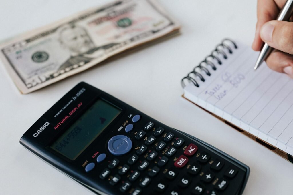 A calculator and budget worksheet on a desk with handwritten spending notes