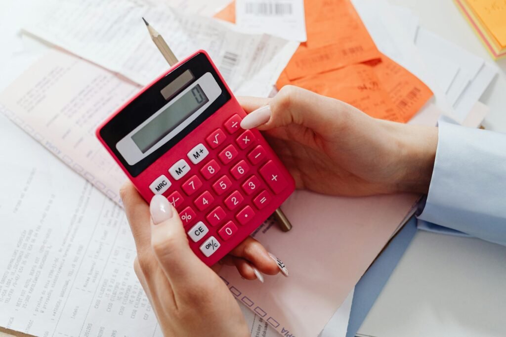 A calculator, grocery receipt, and several herbal tea boxes beside a mug on a kitchen table.