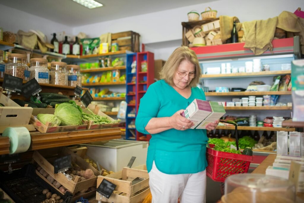 Close-up of a shopper comparing herbal tea boxes and reading the ingredient panel in a grocery store.
