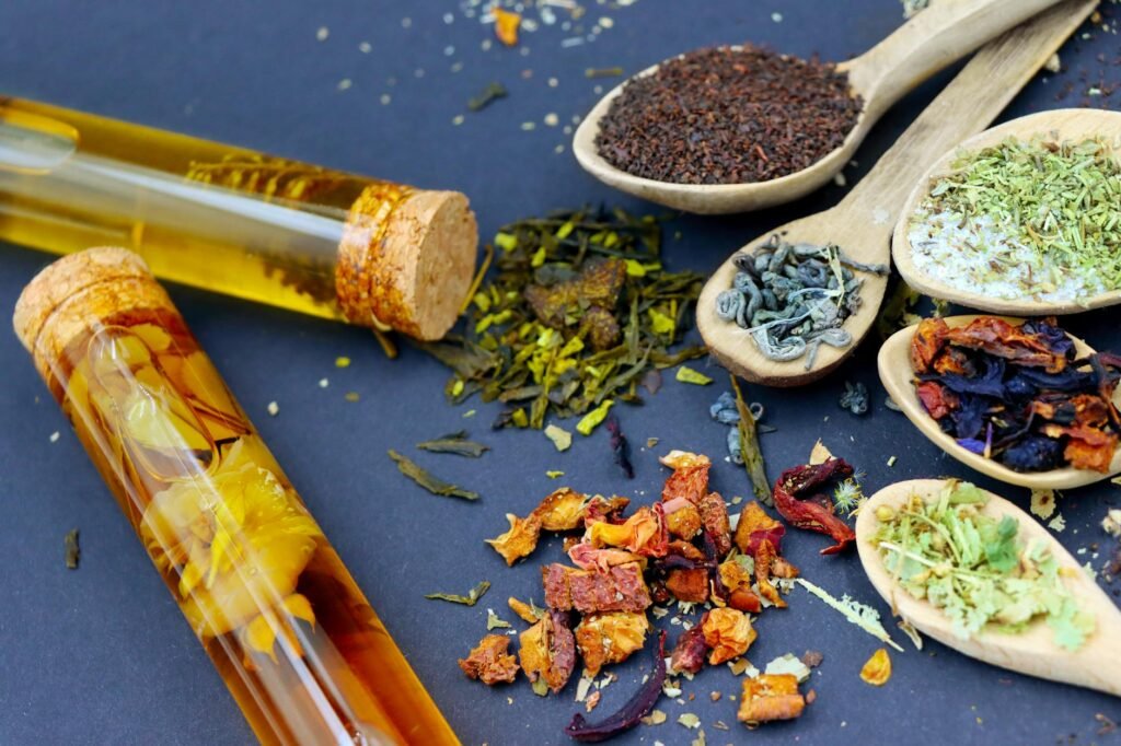 Loose dried herbs in jars beside a tea strainer and mug on a kitchen counter