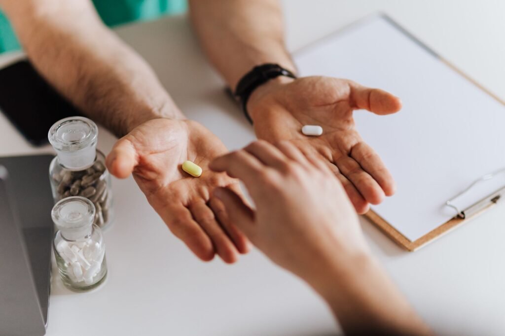 A pharmacist speaking with a customer while reviewing medicines and supplement bottles.